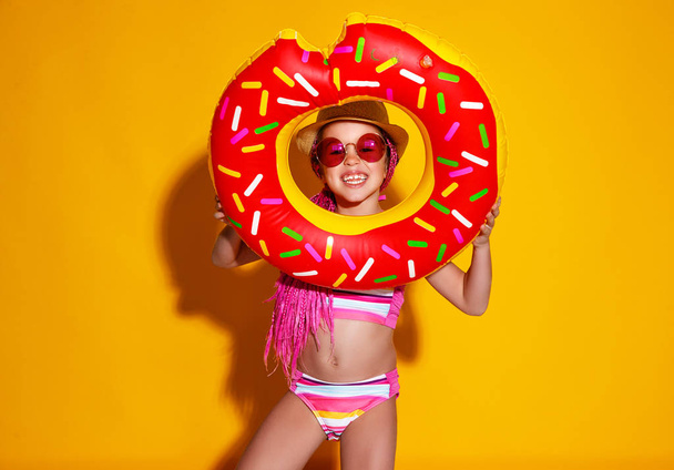 szczęśliwe dziecko dziewczyna w stroju kąpielowym z pływania pierścień pączek na kolorze - Zdjęcie, obraz