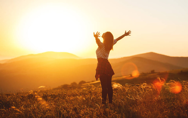 Femme heureuse sautant et profitant de la vie au coucher du soleil dans la montagne
 - Photo, image