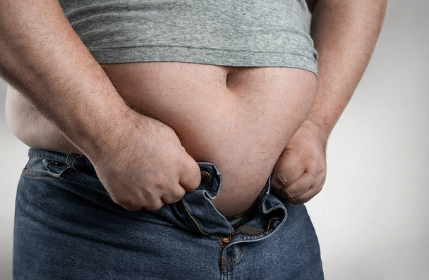Close up van overgewicht man probeert te dragen kleine jeans - Foto, afbeelding
