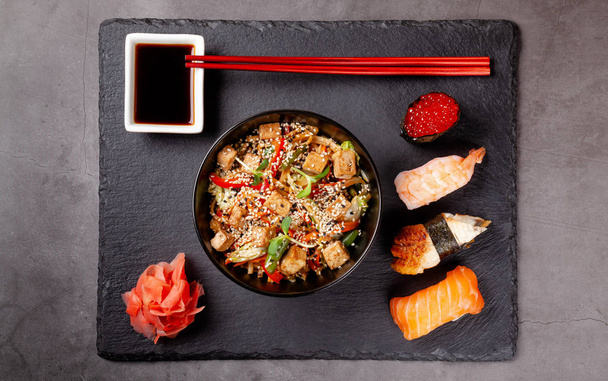 The concept of Japanese cuisine. Japanese lunch of noodles, sushi with shrimp, red caviar, eel, tuna. Soy sauce and red chinese sticks. background image. Top view, copy space - Photo, Image