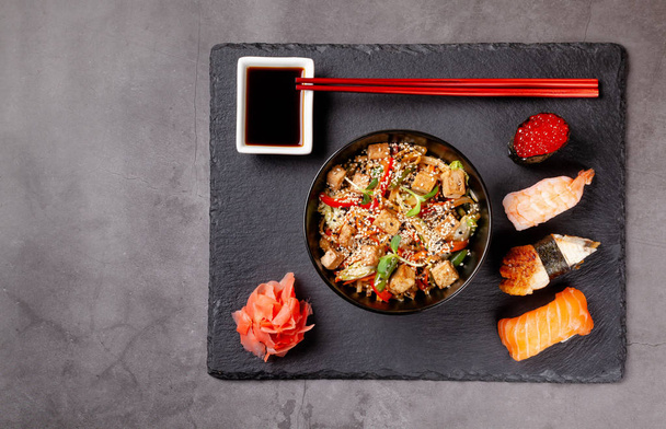 The concept of Japanese cuisine. Japanese lunch of noodles, sushi with shrimp, red caviar, eel, tuna. Soy sauce and red chinese sticks. background image. Top view, copy space - Photo, Image