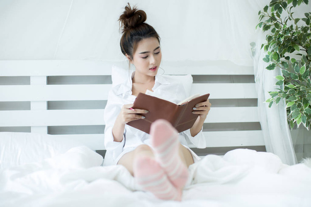 Lifestyle happy young Asian woman enjoying lying on the bed read - Photo, image