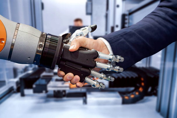 Hand of a businessman shaking hands with a Android robot. - Photo, image