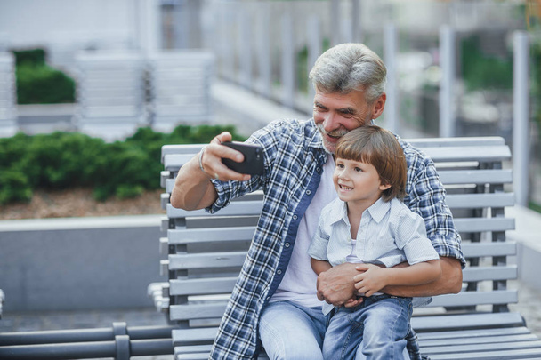 Handsome senior man taking selfie with smiling grandson outdoors - Fotografie, Obrázek
