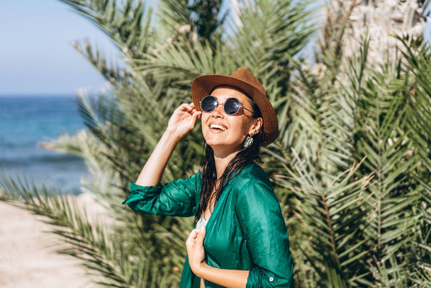 Cute pan asian girl in hat and sunglasses in green pareo walking - Photo, Image