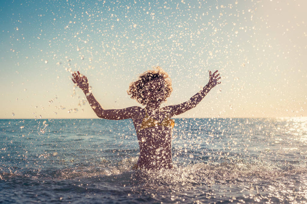 Ευτυχισμένο παιδί παίζοντας μέσα στη θάλασσα. Το παιδί έχει τη διασκέδαση στις καλοκαιρινές διακοπές. Έννοια του δραστήριου τρόπου ζωής - Φωτογραφία, εικόνα