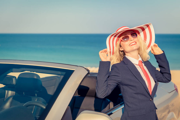 Successful young businesswoman on the beach. Woman standing near the cabriolet classic car. Summer vacations and freedom travel concept - Photo, Image