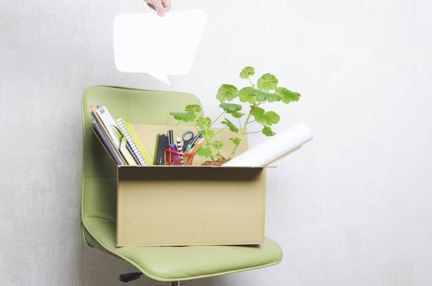 Concepto de despido y pensamientos de los empleados sobre eso.Caja de cartón con papelería en silla de oficina verde
 - Foto, Imagen