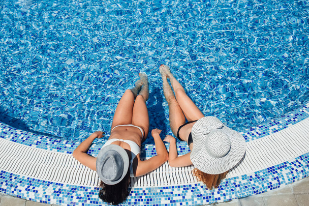 elevated view of two young beautiful women sunbathing at pool - Fotografie, Obrázek