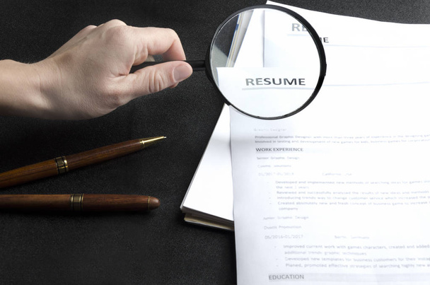 Recruiter`s workplace, pile of resume examples,stationary,hand holding magnifier - Photo, Image