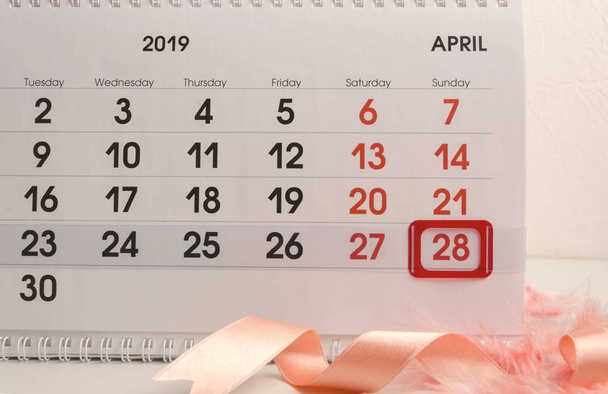 Primer plano del calendario con marca roja en el Día de Pascua, cinta y plumas.Concepto de preparación enemiga celebración de Pascua
 - Foto, Imagen
