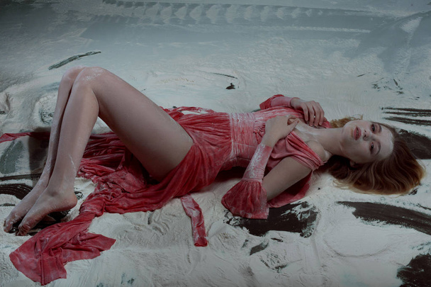 Жінка в червоній сукні лежить в борошні
. - Фото, зображення