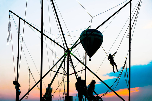Bungee-Jumping und Luftballon. Silhouetten von Kindern vor dem Hintergrund des Sonnenuntergangs. - Foto, Bild