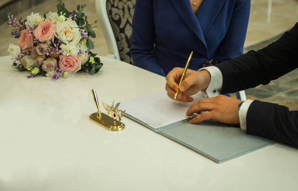 Hands of groom signing marriage contract and bridal bouquet, sel - Valokuva, kuva