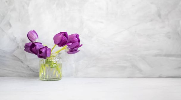Ramo de tulipanes púrpura primavera en un jarrón sobre fondo de hormigón gris
 - Foto, Imagen