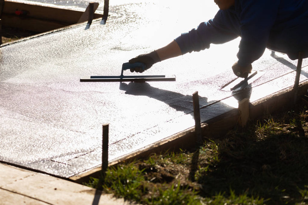 Ciment humide de lissage de travailleur de la construction avec des outils de truelle
 - Photo, image