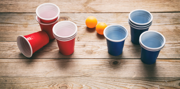 Μπύρα pong. Πλαστικό κόκκινο και μπλε χρώμα κύπελλα και μπάλες Πινγκ πονγκ σε ξύλο - Φωτογραφία, εικόνα