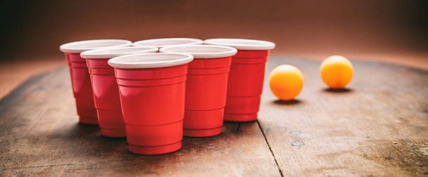 Birra pong. Tazze di colore rosso plastica e palline da ping pong su sfondo di legno
 - Foto, immagini
