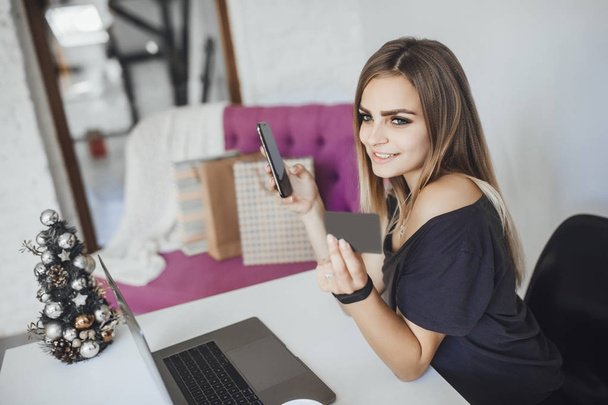 Mladá krásná žena držící kreditní karty, mobilní telefon a používat přenosný počítač - Fotografie, Obrázek