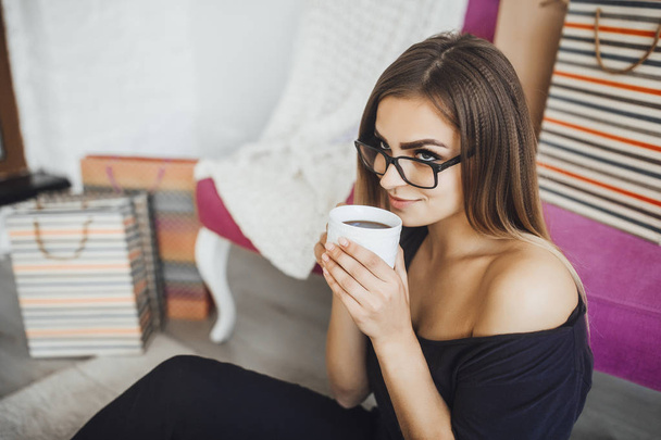 young beautiful woman drinking hot chocolate after successful online shopping at home - Foto, Imagem