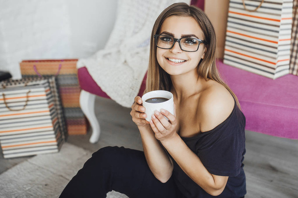 young beautiful woman drinking hot chocolate after successful online shopping at home - Fotografie, Obrázek
