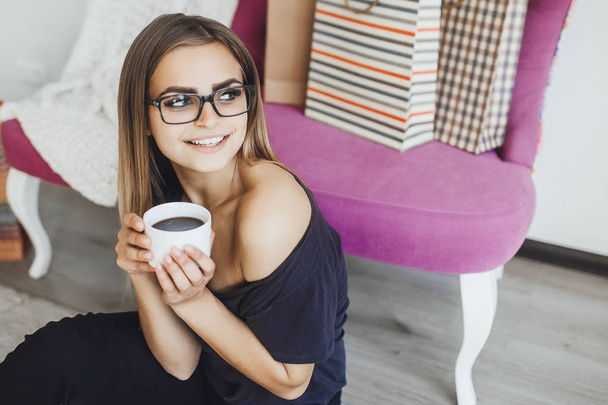 young beautiful woman drinking hot chocolate after successful online shopping at home - Foto, imagen