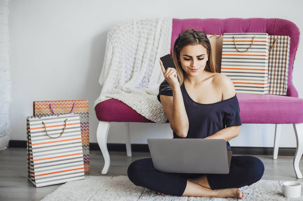 Young beautiful woman holding credit card and using laptop at home on floor - Foto, Bild