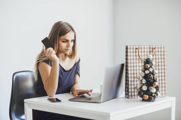 Young happy beautiful woman holding credit card and doing new year online shopping - Photo, Image
