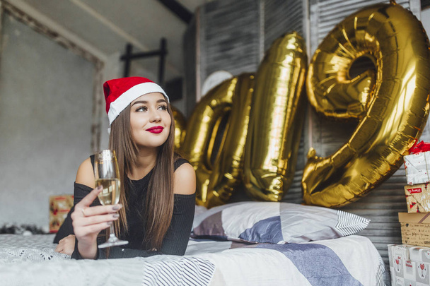 woman in christmas hat drinking champagne at bedroom - Фото, зображення