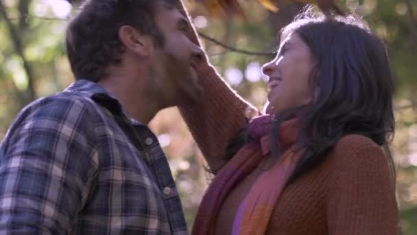 秋の間に森の中で男の頭の上に葉を投げる若い女性 - 映像、動画