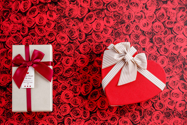 Two boxes of gifts with a ribbon on a red background. The concept is suitable for love stories, birthdays and Valentine's Day - Valokuva, kuva
