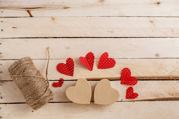 Handmade cardboard hearts on a wooden background. The concept is suitable for love stories and for Valentine's Day - Photo, Image