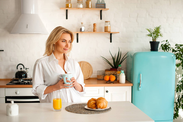 Mujer con camisa blanca bebiendo café con croissants
 - Foto, Imagen