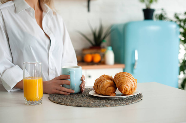 Mujer con camisa blanca bebiendo café con croissants
 - Foto, imagen