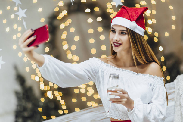 woman in christmas hat making selfie, celebrating new year  - Фото, изображение