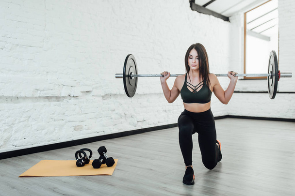 Portrait of woman lifting crossfit against white wall - Foto, afbeelding