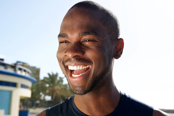 Close up portrait of handsome young black man laughing outdoors - Foto, Bild