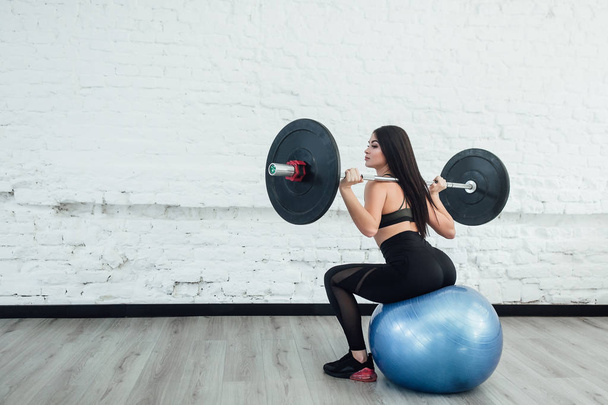 young woman doing weight lifting workout at gym turning back - Fotó, kép