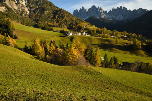 Santa Magdalena Dorf in val di funes in den italienischen Dolomiten. Herbstlicher Blick auf das Tal mit bunten Bäumen und Geißelgebirgsgruppe im Hintergrund bei Sonnenuntergang. Italien. - Foto, Bild