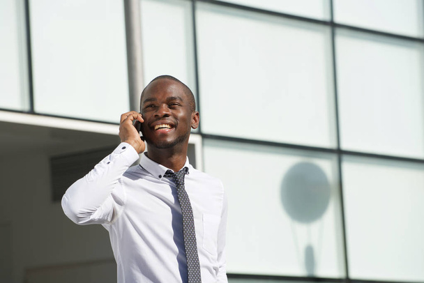 Portrait d'un homme d'affaires souriant parlant avec un téléphone portable en ville
 - Photo, image
