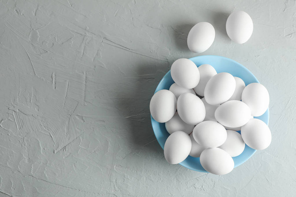 Chicken eggs in plate on gray background, space for text - Fotografie, Obrázek