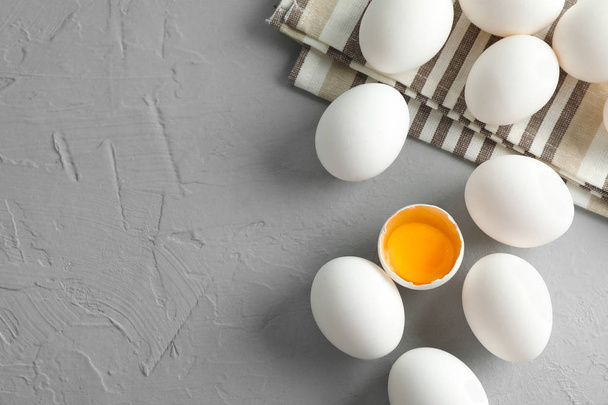 Κοτόπουλο αυγά σε πετσέτα κουζίνας σε γκρίζο φόντο, χώρο για το κείμενο - Φωτογραφία, εικόνα