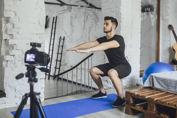 fitness blogger recording video of how to properly squat during sports  - Foto, Bild