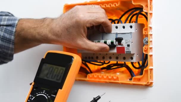 Video van de handen van de elektricien technicus die met de multimeter meet de spanning in een elektrisch schakelbord van een residentiële installatie. Bouw. - Video