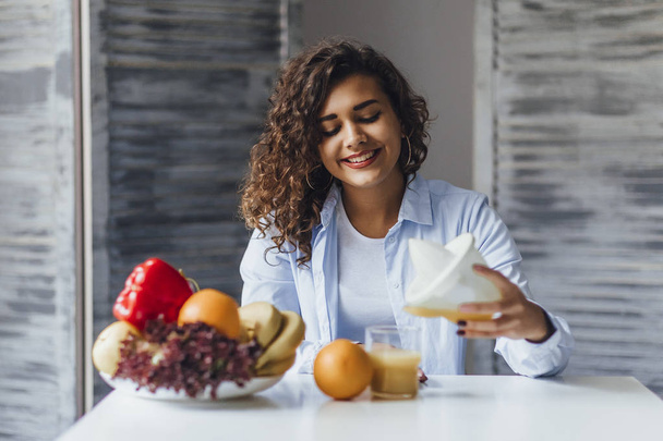young beautiful woman pouring freshly squeezed juice from vegetables and fruits - Photo, Image