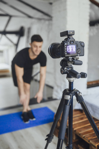 handsome fitness blogger recording video for blog and showing exercises for workout - Foto, afbeelding