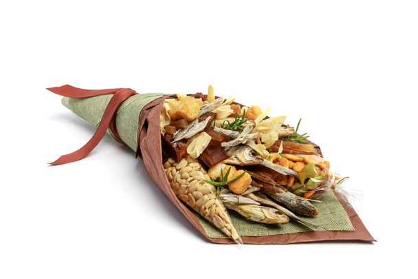 Original bouquet consisting of dried salted fish, salted peanuts, crackers, dried bread and other beer snacks isolated on white background as male gift - Photo, image