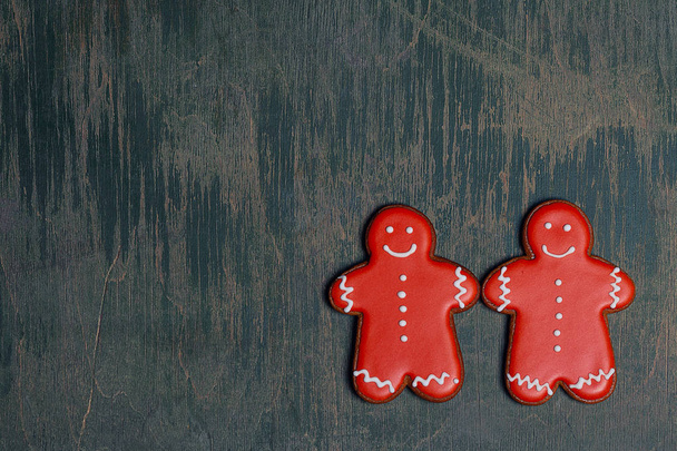 Christmas red gingerbread men cookies lying in the center of old table - Photo, image