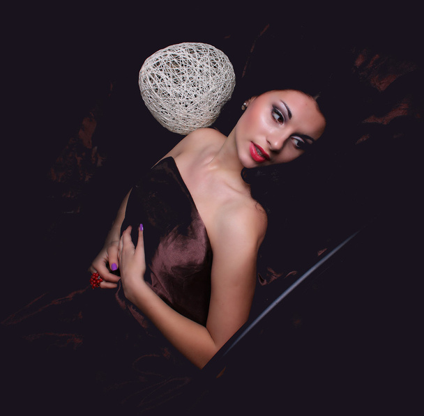 sexy nackte junge kaukasische erwachsene Frau mit roten Lippen, langen schwarzen Haaren und einer gepiercten Augenbraue, bedeckt mit einem dunklen Satintuch - Foto, Bild