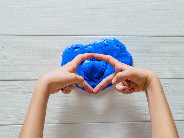 Le mani di bambino mostrano il cuore di melma sopra azzurra
. - Foto, immagini